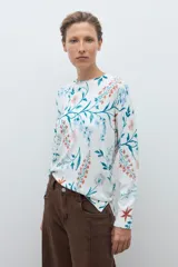 Sweater de punto fino con estampado floral en tonos azules, naranjas y verdes sobre base color crudo. Presenta cuello redondo y mangas largas.