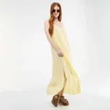 Vestido largo fluido de color amarillo pastel, con tirantes finos, escote en V y tajo lateral.