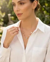 Collar de acero con baño de oro, compuesto por una cadena fina con dijes en forma de flor distribuidos a lo largo de la misma, con incrustaciones de nácar y circonia.