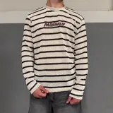 Sweater tejido a rayas horizontales color crema y marrón, con cuello redondo y logo bordado en el pecho.