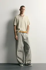 Pantalón barrel fit de mezclilla color verde militar, con efecto lavado, cinco bolsillos, cierre frontal con cremallera y botón, y detalle de pinzas en las rodillas.