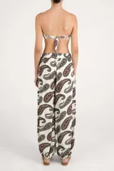 Pantalón de corte fluido color beige con estampado paisley en tonos oscuros, tiro alto con lazo para anudar en la cintura y botamangas con elástico.
