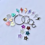 Set de aros de acero quirúrgico hipoalergénico con dijes intercambiables de diferentes formas y colores: corazones holográficos, estrellas metalizadas y rayos de colores.