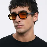 Lentes de sol cuadrados con ángulos redondeados, montura fina negra y lentes color naranja.