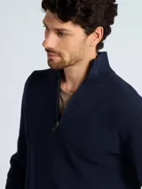 Sweater de punto color verde oscuro, con cuello alto y cierre frontal parcial, de manga larga y puños acanalados.