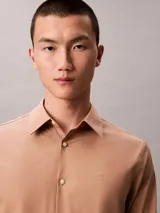 Camisa de manga larga Calvin Klein con corte slim, cuello de punta clásico, cierre frontal con botones a tono y monograma bordado sutilmente en el pecho.