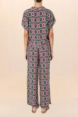 Camisa verde con estampado de cadenas entrelazadas en tonos verde oscuro, blanco y fucsia, de mangas cortas y cuello camisero.