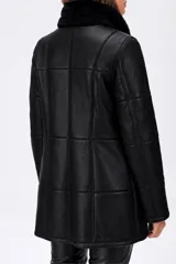 Abrigo midi de cuero negro con cuello de piel sintética, cierre frontal con botones y diseño de paneles estructurados.