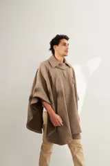 Poncho unisex de lana fina color marrón claro con cuello, cartera con broches a presión y bolsillo ojal. Diseño exclusivo de Don Baez, hecho 100% en Uruguay.