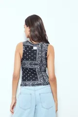 Top crop sin mangas color rojo con estampado tipo bandana en blanco y negro. Tiene cuello cerrado y sisas definidas.