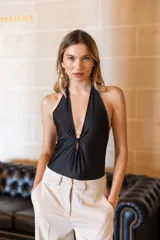 Body negro con escote halter y abertura en el centro del pecho con detalle de aro metálico.