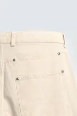 Pantalón relaxed fit color beige, confeccionado en tejido de algodón. Cuenta con bolsillos frontales, bolsillos traseros de plastrón y aplicación de bolsillos plastrón con tira multifunción en la pernera. Cierre frontal con cremallera y botón.