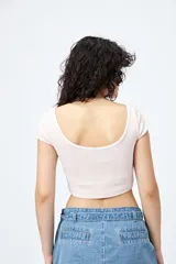 Top corto negro de punto acanalado con escote redondo, mangas cortas y ribetes blancos en cuello y mangas.