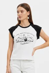 Remera al cuerpo con diseño raglán, color blanco en el torso y azul marino en las mangas cortas y el cuello. Cuenta con un estampado frontal de temática de tenis con las inscripciones "Portofino Tennis" y "Summer Italia".