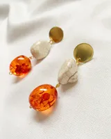 Aros colgantes con base dorada, cuenta de piedra sintética color crema y cuenta de resina traslúcida color naranja.
