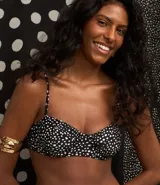 Top de bikini negro con estampado de lunares blancos, corte media taza con breteles ajustables y lazo en la espalda. Confeccionado en microfibra.
