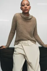 Jersey de punto calado color beige, con cuello alto vuelto y manga larga, confeccionado en lino.