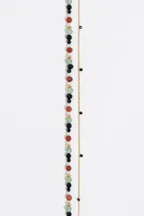 Collar de doble cadena dorada compuesto por una cadena de eslabones finos y una hilera de cuentas de granito en colores negro, rojo, verde y blanco. Incluye un cierre de barra y aro y un dije en forma de corazón esmaltado en negro.