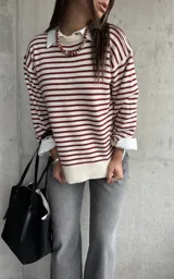 Sweater de punto con diseño a rayas horizontales en color rojo y crema, de corte holgado, cuello redondo y mangas largas con puños abotonados.