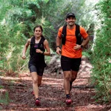 Mochila chaleco de hidratación Merrell en color negro, diseñada para running y trail running, con múltiples bolsillos frontales, cordones de ajuste y tejido de malla transpirable.