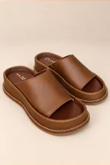 Sandalias de cuero color marrón chocolate, de plataforma plana con vira cosida y tira ancha superior.