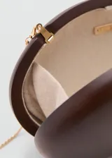 Bolso clutch rígido de madera color marrón, de forma ovalada, con cierre superior metálico dorado con detalle de nudo y forro interior de poliéster.