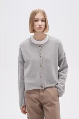 Cardigan de tejido de punto gris, con cuello redondo, cierre frontal con botones y mangas largas de corte holgado.