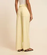 Pantalón wide leg color amarillo pálido confeccionado en viscolino, con tiro alto, trabilla con cinturón en metal, hebilla redonda y cierre por encaixe.