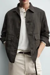 Sobrecamisa relaxed fit confeccionada en tejido de lino de color negro, con cuello solapa, manga larga con puño abotonado, bolsillos de plastrón en la cadera y cierre frontal de botones.