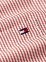 Camisa de poplin a rayas rojas y blancas, con cuello camisero clásico, cierre con botones, bolsillo de parche en el pecho, manga larga y logo de Tommy Hilfiger bordado en el pecho.