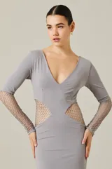 Vestido largo color gris con escote en V, mangas largas y aberturas laterales con tejido de red metálica que se extiende desde la cintura hasta los antebrazos.