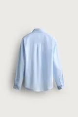 Camisa regular fit de manga larga con diseño a rayas verticales celestes y blancas. Cuenta con cuello abotonado, bolsillo de parche en el pecho y cierre frontal con botones.