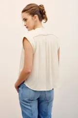 Camisa sin mangas de corte amplio y color fucsia, con cuello mao y cierre frontal de botones ocultos.