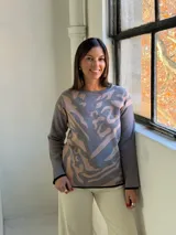 Sweater de punto con diseño estampado abstracto en tonos gris y beige, cuello redondo y terminaciones en color negro.