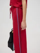 Pantalón de algodón color rojo, de corte holgado y pierna ancha, con pretina elástica y rayas bicolores al costado.