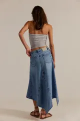 Falda larga de denim, de tiro medio y línea A, con abertura frontal, paneles con costuras y ruedo deshilachado en punta.