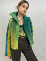 Chaqueta de lana merino afieltrada con diseño en degradé de tonos verdes y amarillos. Presenta un corte recto, cuello alto, mangas largas y bolsillos laterales.