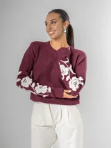 Sweater de tejido de punto color borgoña con escote en V y bordado de flores blancas en las mangas.
