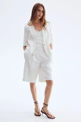 Blazer blanco de sarga con manga corta, botonadura sencilla con un botón, solapas de muesca y bolsillos delanteros ribeteados.