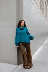 Buzo de tejido de punto en mezcla de lana y alpaca, color gris. Presenta una silueta amplia con cuello tipo polo que incluye broches para convertirlo en polera, mangas largas con puños y un diseño de tejido horizontal.