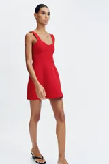 Vestido corto de color rojo con escote corazón estilo corsetero, tirantes anchos y falda con corte evasé. Cuenta con cierre de cremallera oculto en la espalda.