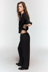 Pantalón fluido de tiro alto color verde militar, con cintura elástica ajustable con cordones y detalles de cuentas de madera. Tiene bolsillos delanteros y pierna recta.