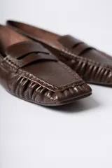 Mocasín de cuero marrón con textura arrugada, diseño de puntera cuadrada con detalle de costuras fruncidas en los laterales y banda frontal clásica.
