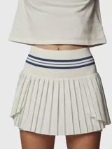 Falda tipo skort con diseño plisado, cintura alta elástica con detalle de rayas horizontales en contraste. Incluye short integrado con bolsillo funcional, confeccionada en tejido técnico de secado rápido.