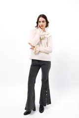 Buzo de tejido acanalado color lila, con cuello redondo decorado con dos volados y mangas largas con tres volados pequeños en los puños.