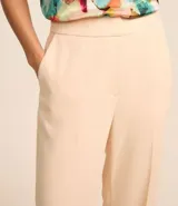 Pantalón de vestir color beige, de corte recto, con cintura alta y cierre tradicional con cremallera.