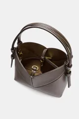Bolso tipo mini shopper de estructura rígida en color crudo, con detalles de costuras en contraste y ribetes en color marrón oscuro. Cuenta con un asa de mano fija y cierre superior.