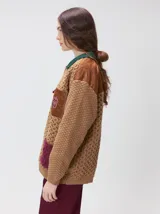 Campera tejida de punto grueso en color beige, con cuello en contraste color verde. Presenta cierre frontal con botones, bolsillos delanteros con apliques en nylon color marrón y bordado decorativo, y forro interno de nylon.