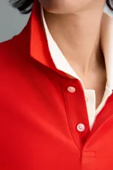 Polo de manga larga color rojo, confeccionado en tejido de algodón con estructura piqué, cuello solapa y cierre frontal de botonadura. Presenta aberturas laterales en el bajo.