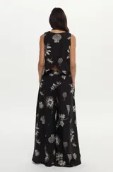 Pantalón palazzo negro con estampado artesanal en tonos claros, cintura elastizada, bolsillos laterales y aberturas en las piernas.